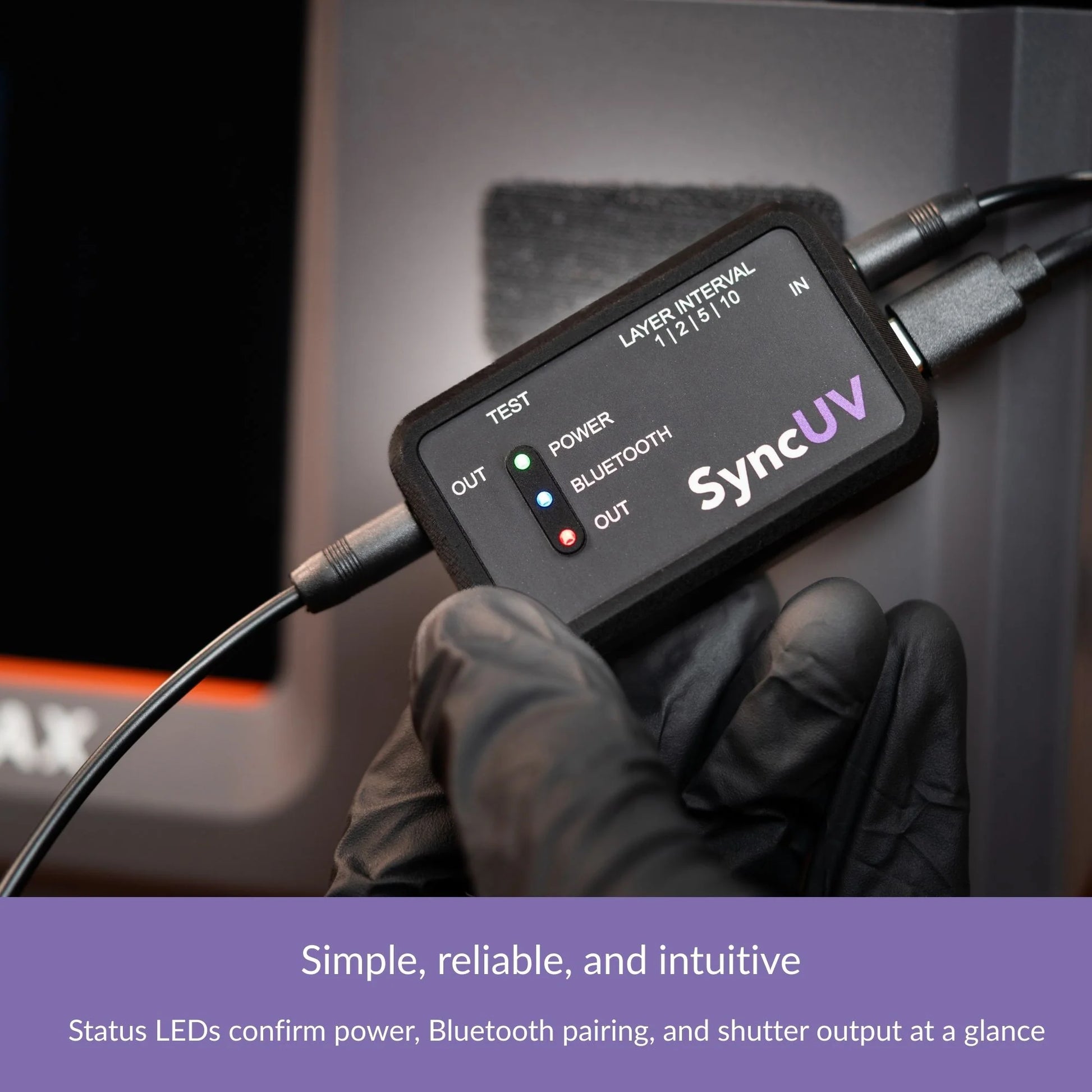 Hand holding the SyncUV Hub connected by cables, with status LEDs lit.